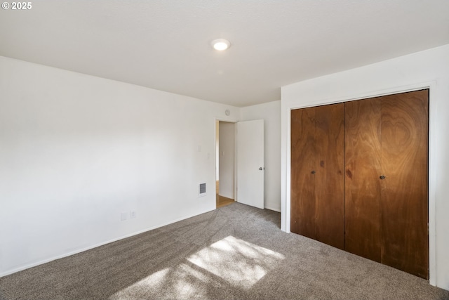 unfurnished bedroom featuring a closet, carpet floors, and visible vents