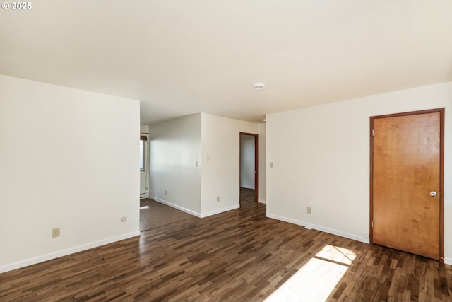 spare room with baseboards and dark wood-style flooring