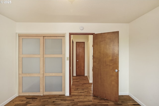 unfurnished bedroom featuring a closet, baseboards, and wood finished floors