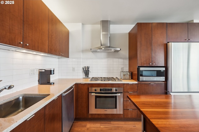 kitchen with appliances with stainless steel finishes, light stone counters, a sink, ventilation hood, and tasteful backsplash