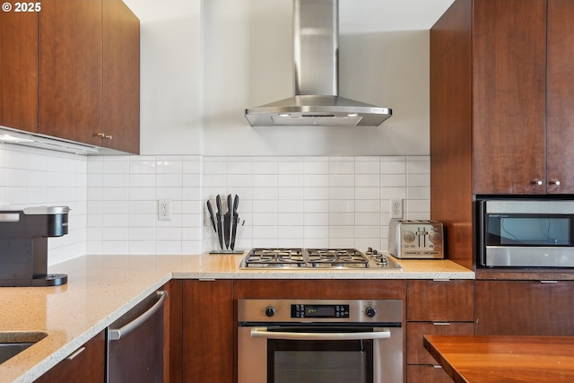 kitchen with wall chimney range hood, appliances with stainless steel finishes, backsplash, and light stone counters