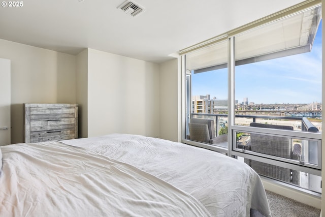 bedroom featuring a view of city, access to outside, visible vents, and carpet
