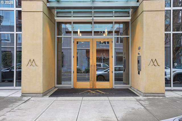 property entrance featuring uncovered parking, french doors, and stucco siding