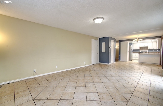 unfurnished living room with light tile patterned floors, a textured ceiling, and an inviting chandelier