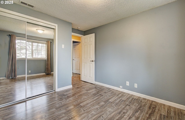 unfurnished bedroom featuring a closet, wood-type flooring, and a textured ceiling