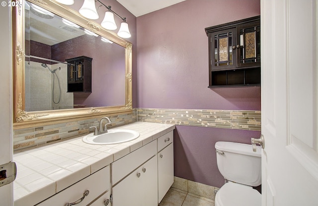 bathroom with tile patterned floors, decorative backsplash, vanity, and toilet