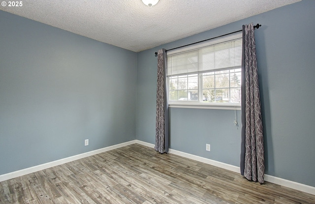 empty room with wood-type flooring and a textured ceiling