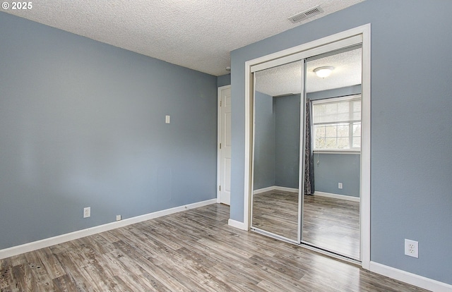 unfurnished bedroom with hardwood / wood-style floors, a textured ceiling, and a closet