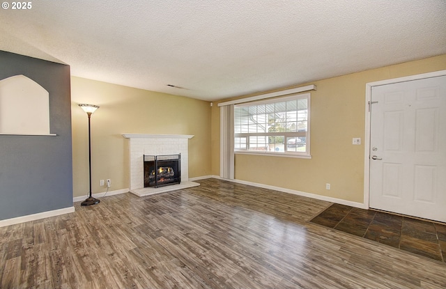 unfurnished living room with a fireplace, wood-type flooring, and a textured ceiling