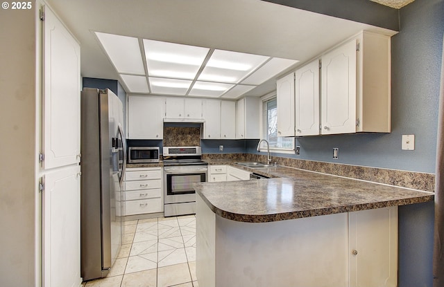 kitchen featuring white cabinets, sink, light tile patterned floors, appliances with stainless steel finishes, and kitchen peninsula