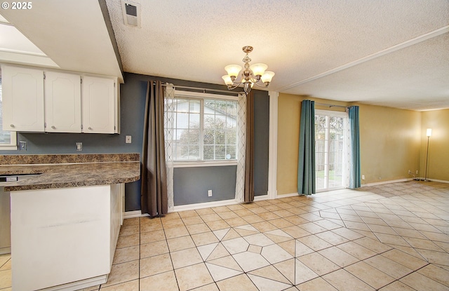 kitchen with white cabinets, light tile patterned floors, a textured ceiling, and a chandelier