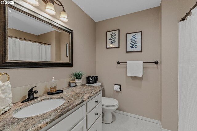 bathroom featuring vanity, baseboards, toilet, and tile patterned flooring