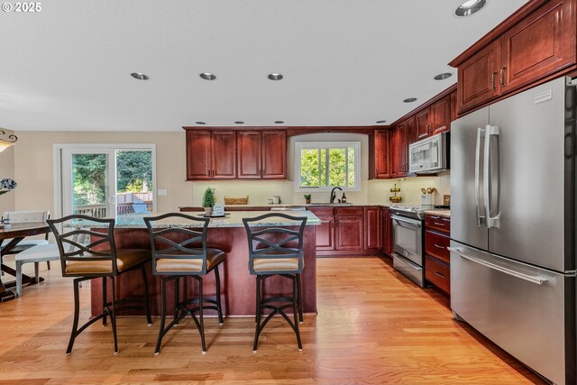kitchen featuring appliances with stainless steel finishes, light wood finished floors, healthy amount of natural light, a kitchen island, and recessed lighting