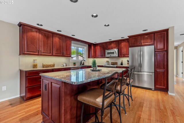 kitchen with stainless steel appliances, dark brown cabinets, light wood-style flooring, and recessed lighting