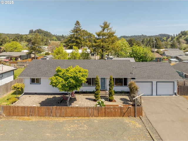 ranch-style home with roof with shingles, a fenced front yard, and an attached garage