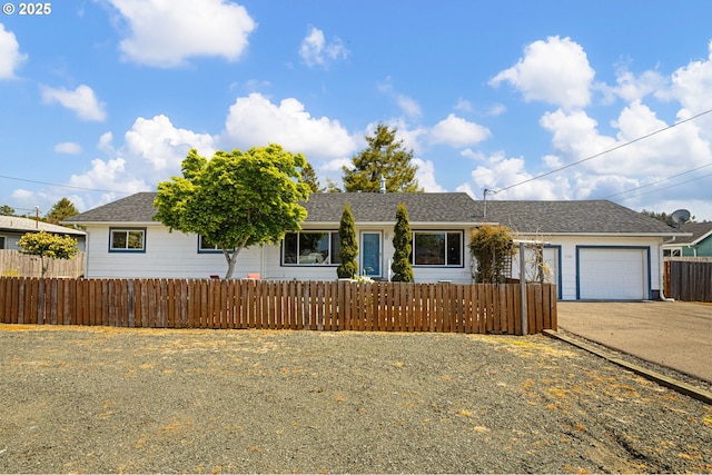 ranch-style house with concrete driveway, a fenced front yard, a shingled roof, and a garage
