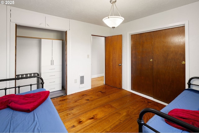 bedroom with a closet, hardwood / wood-style flooring, a textured ceiling, and visible vents
