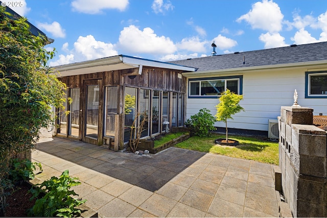 back of property featuring a sunroom, a shingled roof, a patio area, and a fire pit