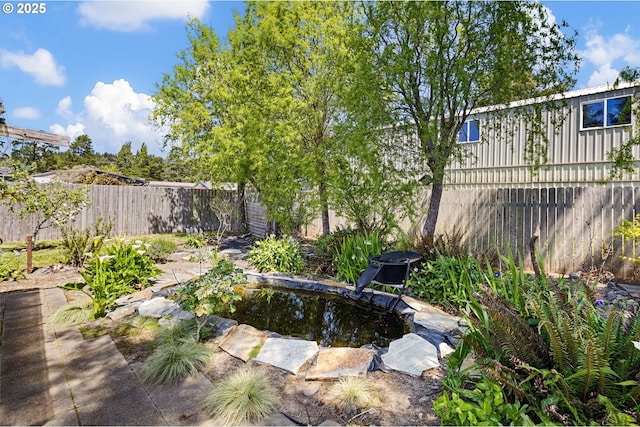 view of yard with a fenced backyard and a garden pond