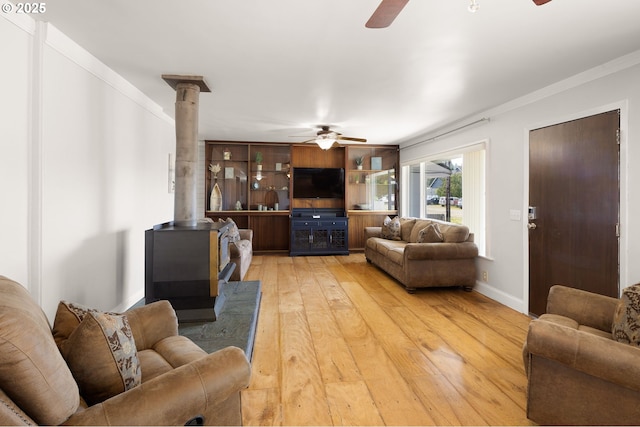living area featuring a ceiling fan, a wood stove, and light wood-type flooring