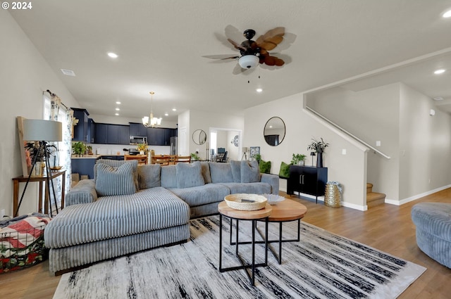 living room featuring ceiling fan with notable chandelier and wood-type flooring