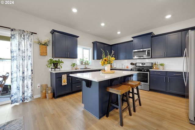 kitchen featuring appliances with stainless steel finishes, a breakfast bar, decorative backsplash, a center island, and light hardwood / wood-style floors