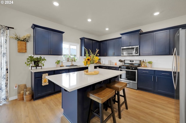 kitchen with a breakfast bar area, blue cabinetry, appliances with stainless steel finishes, light hardwood / wood-style floors, and a kitchen island