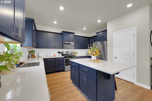 kitchen featuring appliances with stainless steel finishes, a breakfast bar, sink, a center island, and light wood-type flooring