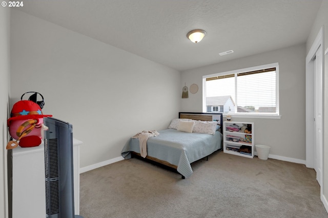 bedroom featuring light colored carpet and a textured ceiling