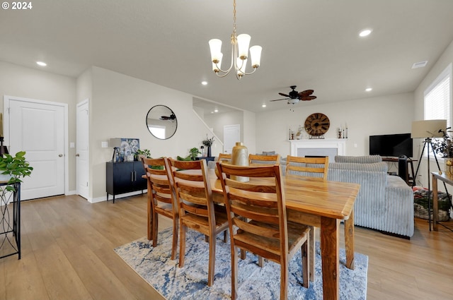 dining space featuring ceiling fan with notable chandelier and light wood-type flooring