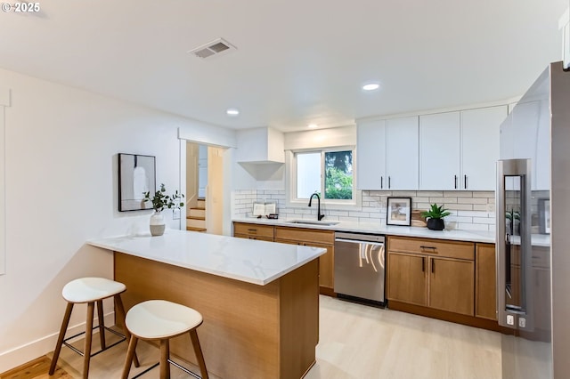 11940 SW Edgewood St, Portland, OR 97225 - kitchen featuring stainless steel appliances, a sink, light wood-type flooring, a breakfast bar area, and brown cabinets