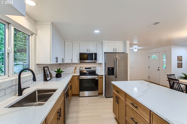 11940 SW Edgewood St, Portland, OR 97225 - kitchen featuring appliances with stainless steel finishes, a sink, decorative backsplash, plenty of natural light, and recessed lighting