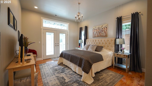 bedroom with hardwood / wood-style flooring, access to exterior, an inviting chandelier, and french doors