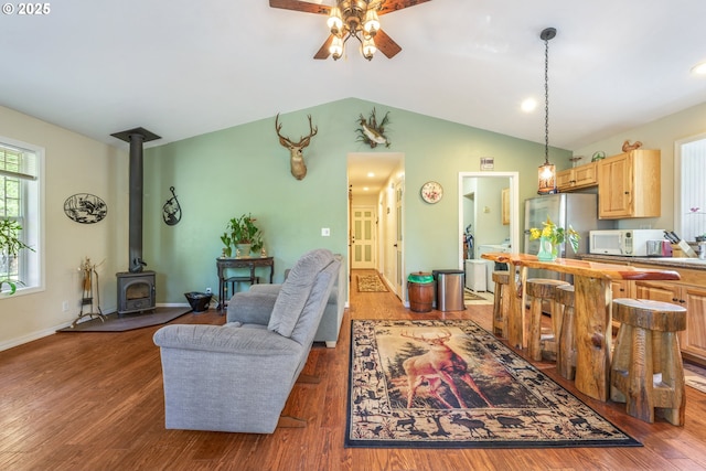 1274 Wild Mustang Ln, Gilchrist, OR 97737 - living room with ceiling fan, wood finished floors, a wood stove, vaulted ceiling, and baseboards