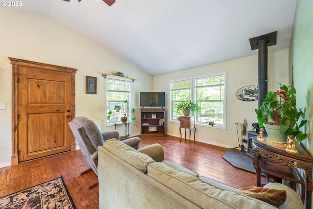 1274 Wild Mustang Ln, Gilchrist, OR 97737 - living area featuring vaulted ceiling, dark wood-style floors, baseboards, a wood stove, and a ceiling fan