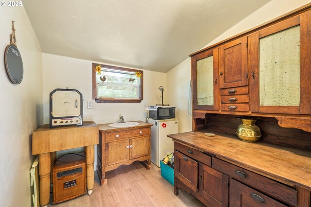 1274 Wild Mustang Ln, Gilchrist, OR 97737 - kitchen with black microwave, a sink, light wood-style flooring, wooden counters, and vaulted ceiling