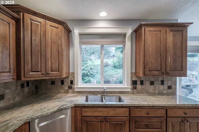 kitchen featuring sink, light stone counters, a textured ceiling, dishwasher, and decorative backsplash