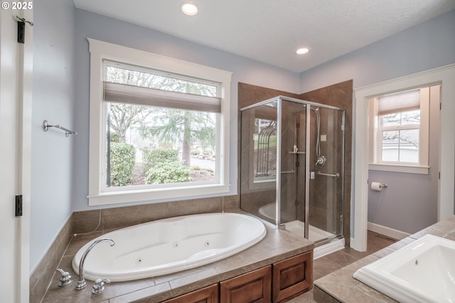 bathroom featuring a healthy amount of sunlight, independent shower and bath, vanity, and a textured ceiling