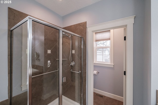 bathroom featuring tile patterned floors, a shower with door, and a textured ceiling