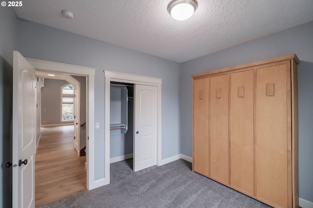 unfurnished bedroom with dark carpet, a closet, and a textured ceiling