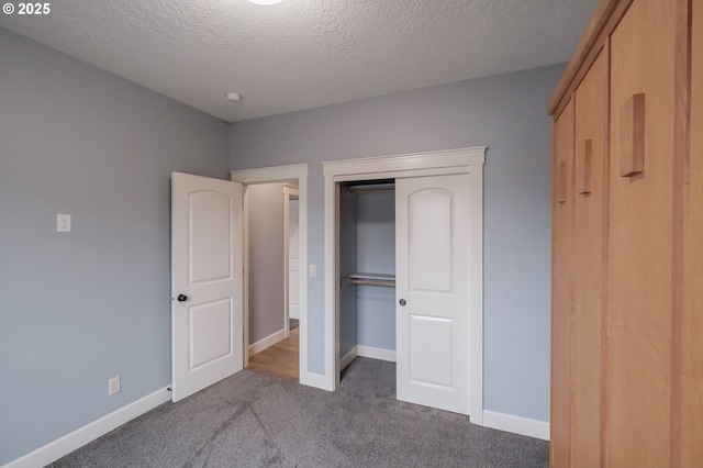 unfurnished bedroom featuring a textured ceiling, dark carpet, and a closet