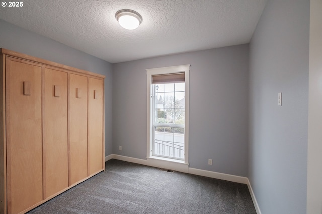 unfurnished bedroom with carpet flooring, a textured ceiling, and a closet