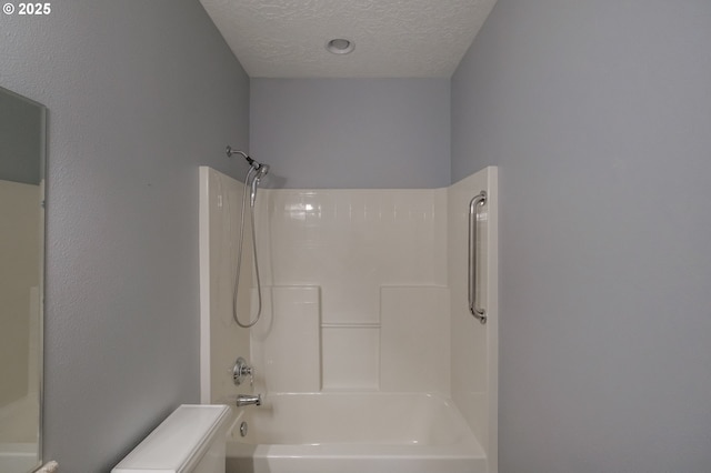 bathroom featuring a textured ceiling, bathing tub / shower combination, and toilet