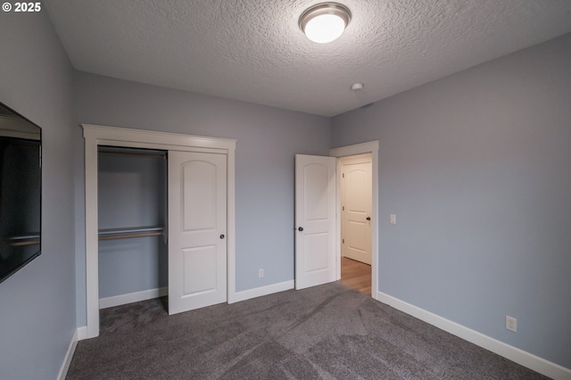 unfurnished bedroom with dark carpet, a closet, and a textured ceiling