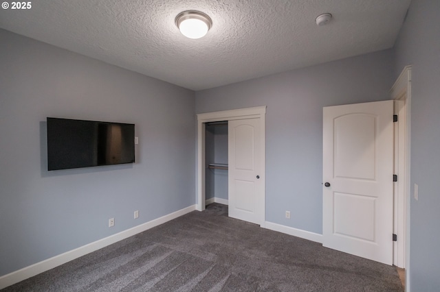 unfurnished bedroom featuring dark carpet, a closet, and a textured ceiling