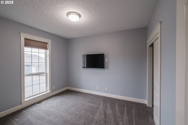 carpeted spare room with a textured ceiling