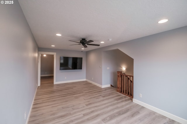 unfurnished living room with a textured ceiling, light hardwood / wood-style floors, and ceiling fan