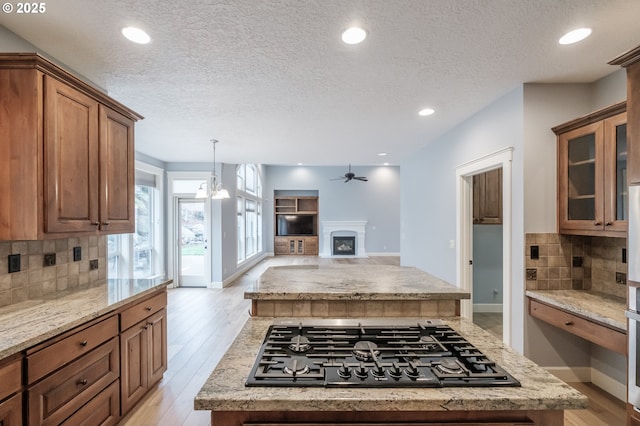 kitchen featuring stainless steel appliances, a kitchen island, light stone countertops, and light hardwood / wood-style floors