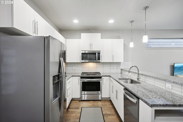 kitchen with white cabinetry, appliances with stainless steel finishes, decorative light fixtures, and sink