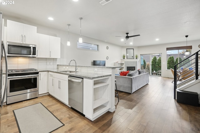 kitchen featuring stainless steel appliances, decorative light fixtures, sink, and white cabinets